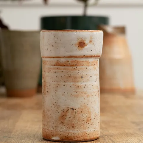 The same vase as photographed, on a wooden table among other pots